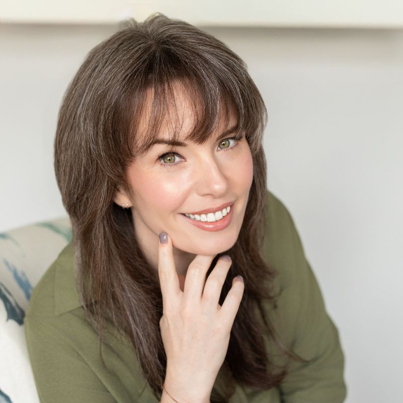 Dr. Kaitlyn Lepore, audiologist, smiling with her hand at her chin in an olive green shirt